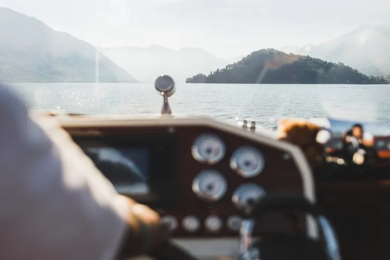 Lake Como mountain view through yacht window. Silhouettes of hills on horizon. Luxury vacations and cruise concept. Boat trip. Yachting in Italy.