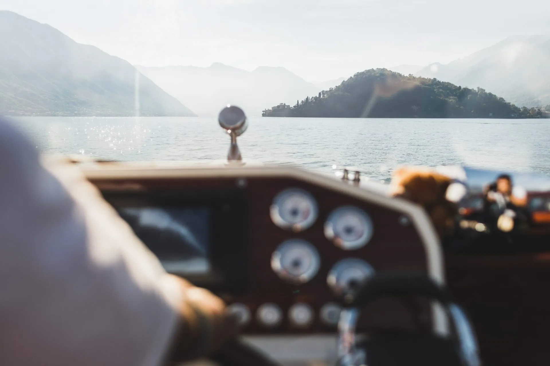 Lake Como mountain view through yacht window. Silhouettes of hills on horizon. Luxury vacations and cruise concept. Boat trip. Yachting in Italy.