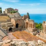 Ruins of the Ancient Greek Theater in Taormina on a sunny summer day with the mediterranean sea. Province of Messina, Sicily, southern Italy.